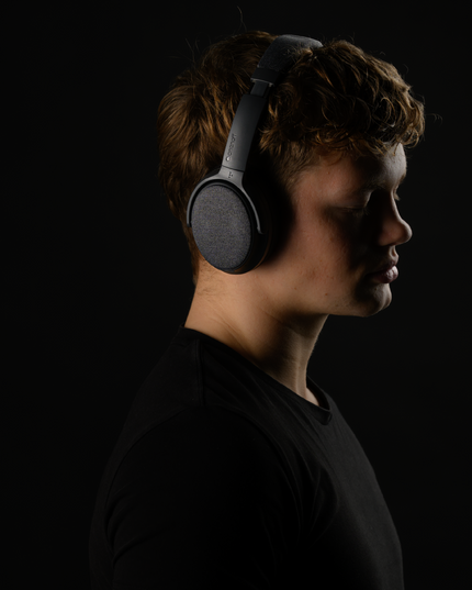 Profile shot of a young man with ONANOFF Dusk Gray Noise Cancelling Headphones.